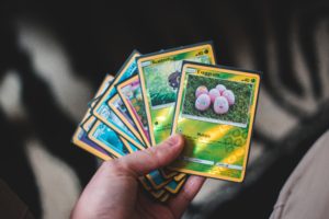 A hand holding a selection of colourful Pokemon cards in a fan shape.