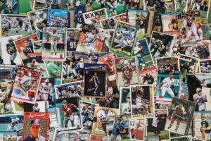 A messy desk covered in colourful sports trading cards.