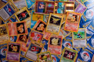 A desk covered with a messy spread of colorful Pokemon cards.