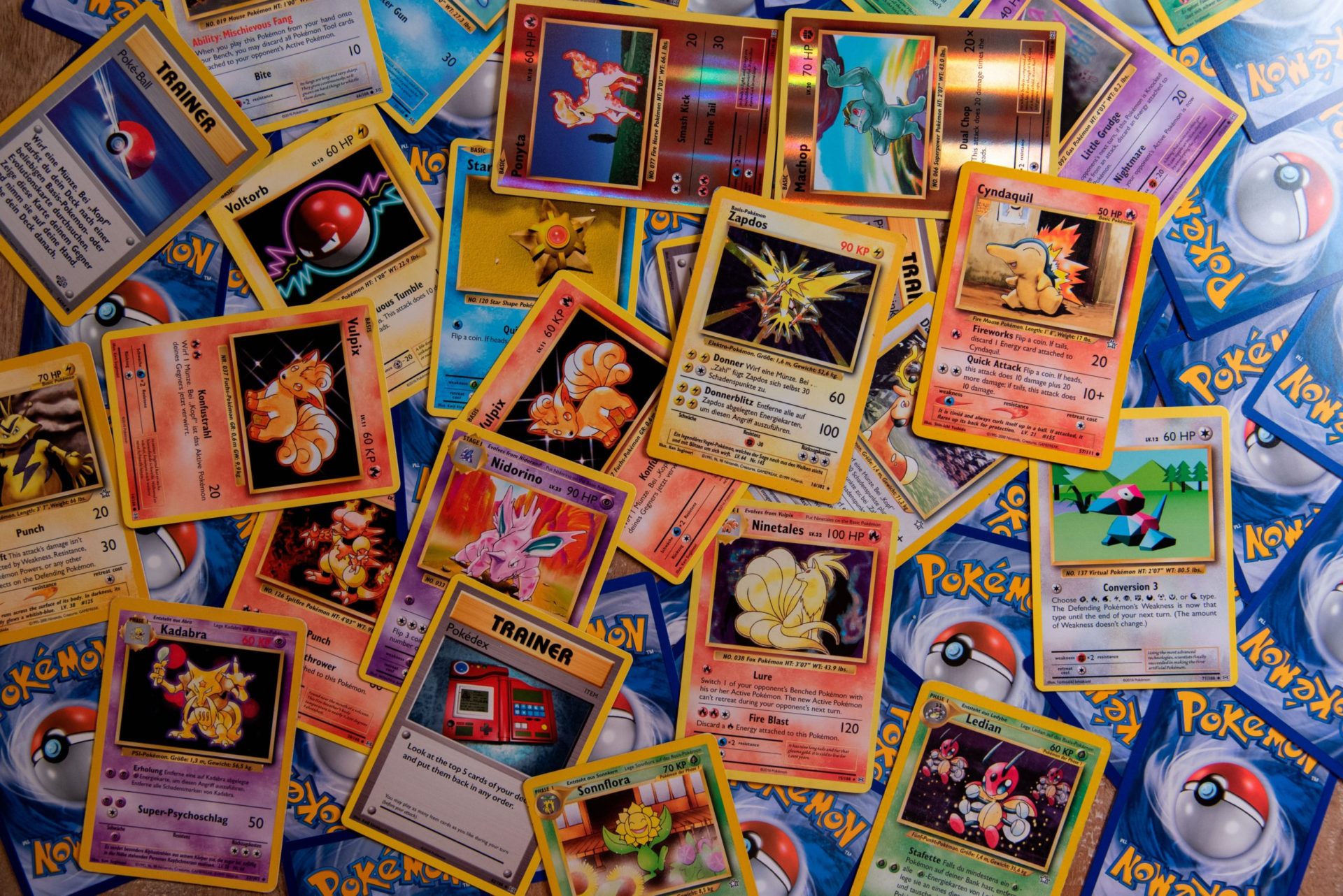 A desk covered with a messy spread of colorful Pokemon cards.